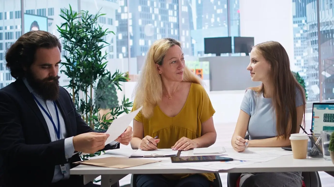 A financial advisor inviting clients to sign official agreement paperwork.