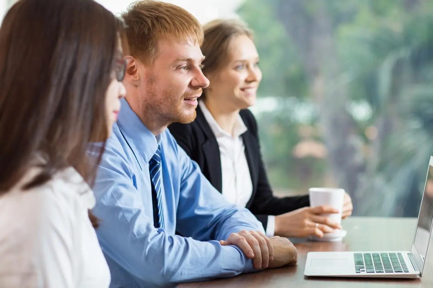 A man and two women are looking at a laptop.